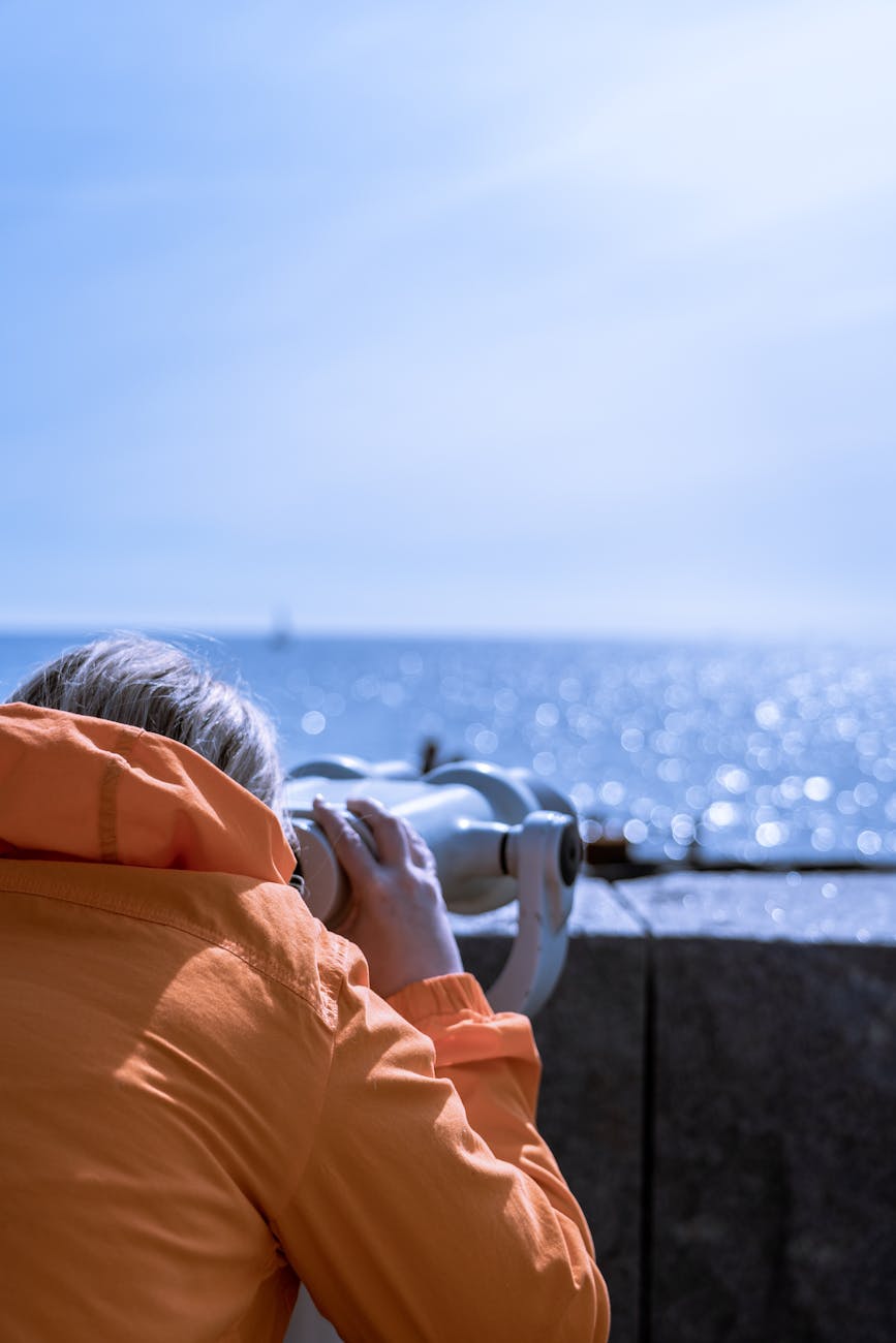 a person in orange jacket using white binoculars