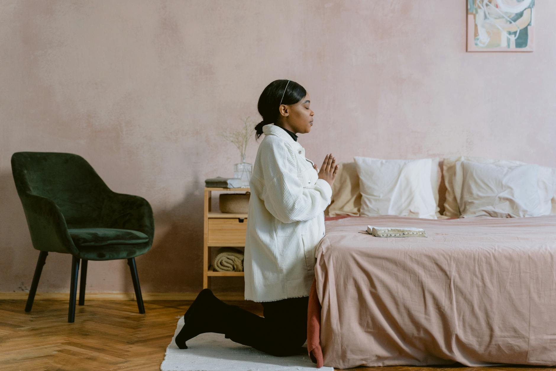 woman in white jacket kneeling while praying