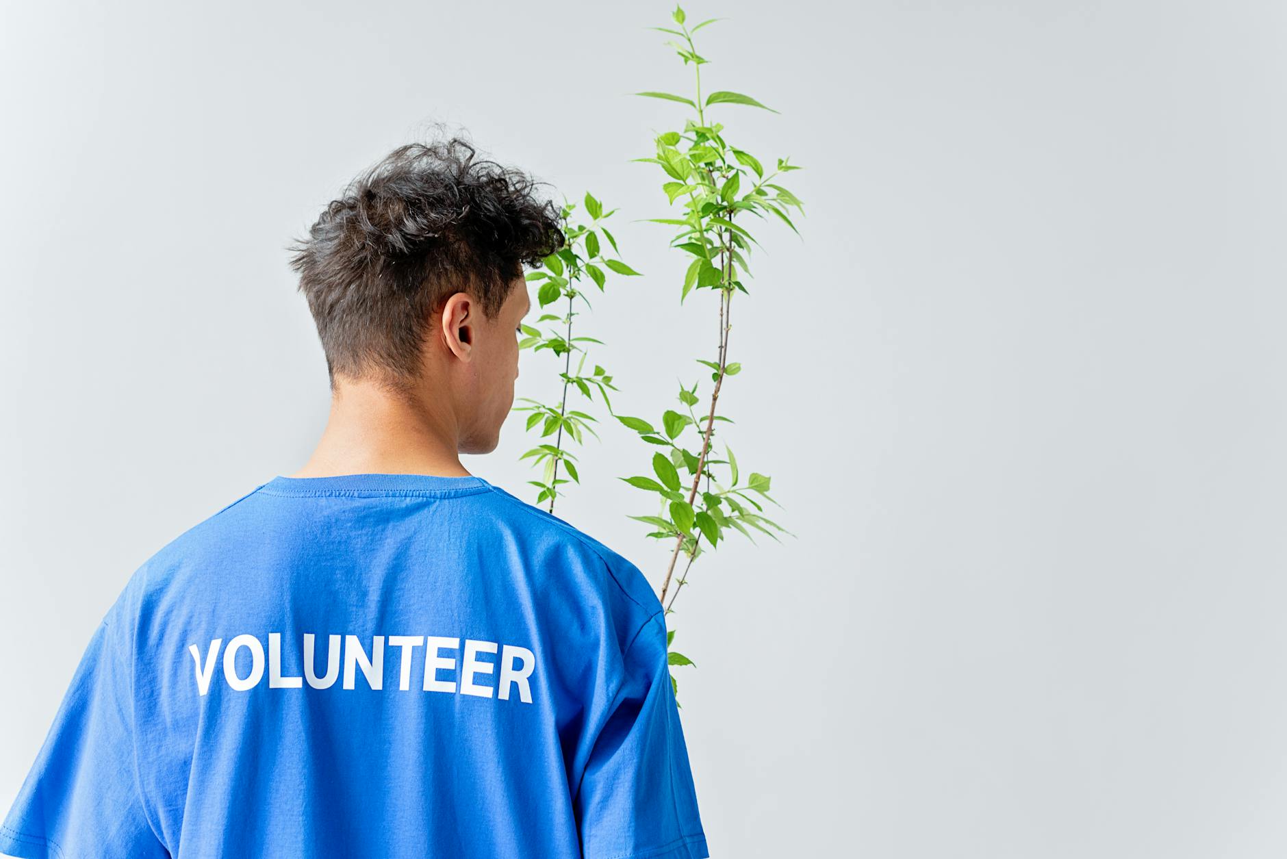 a man in blue shirt holding a green plant