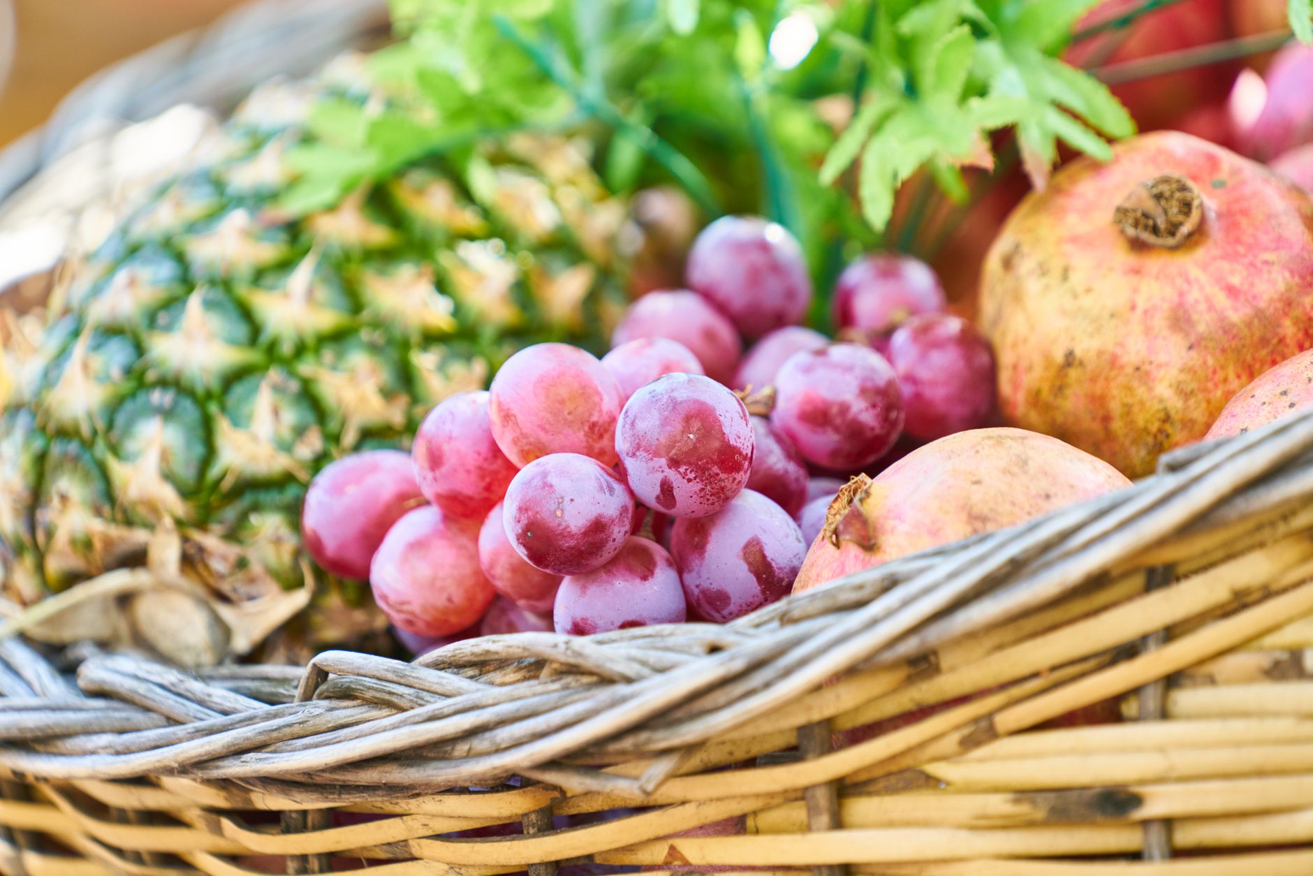 grapes apple and pineapple on brown wicker basket