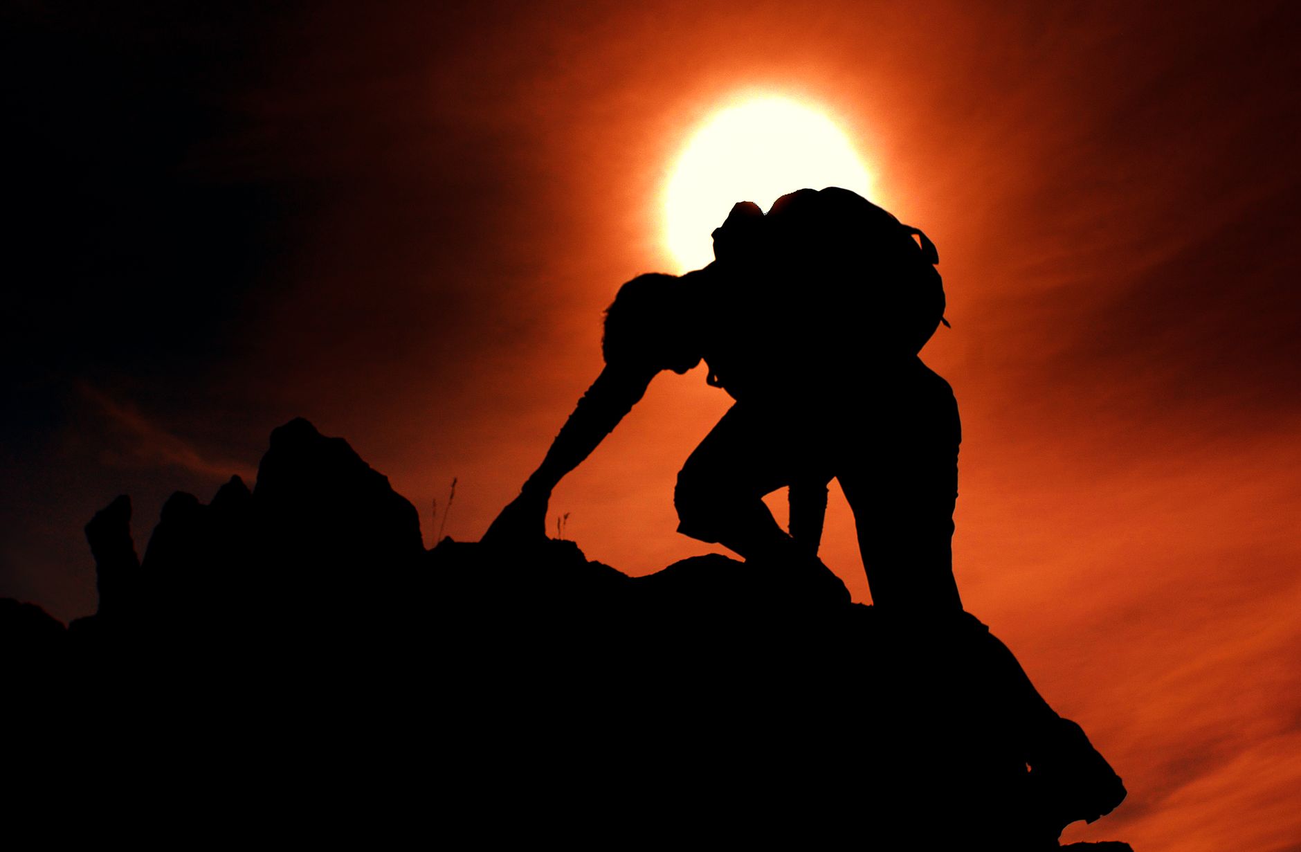 silhouette of man rock climbing